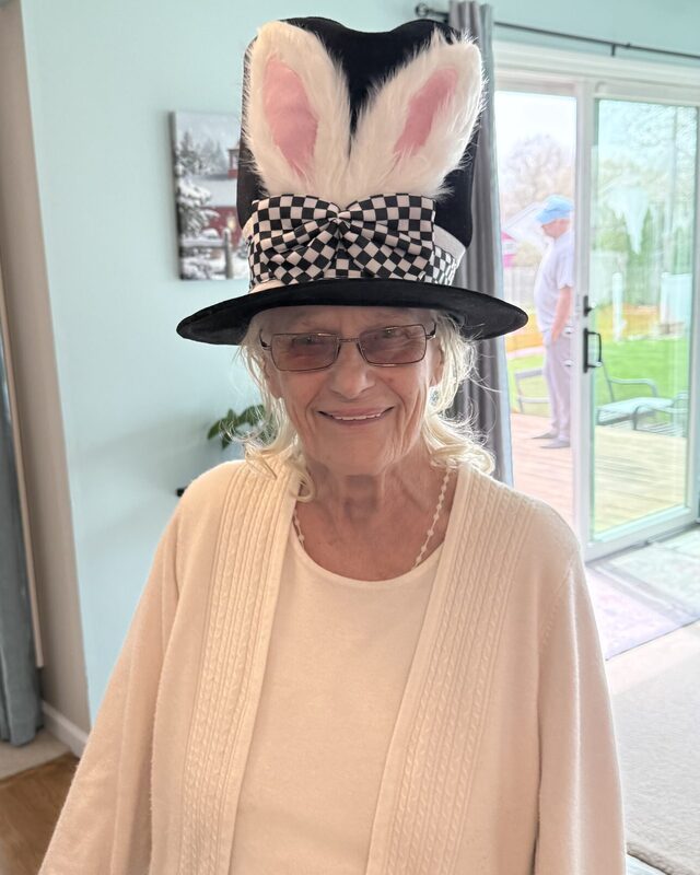 Gale Howell smiling in a black top hat trimmed with rabbit ears and a checkered bow.